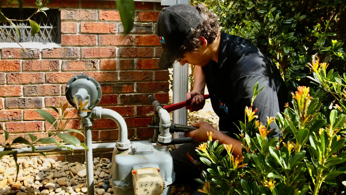 streamline technician working on a gas line repair on a home with a brick exterior