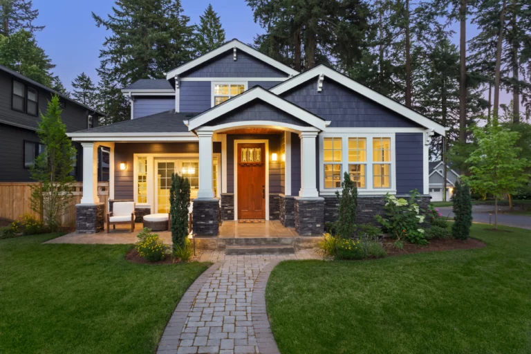 Beautiful home exterior in evening with glowing interior lights and landscaping