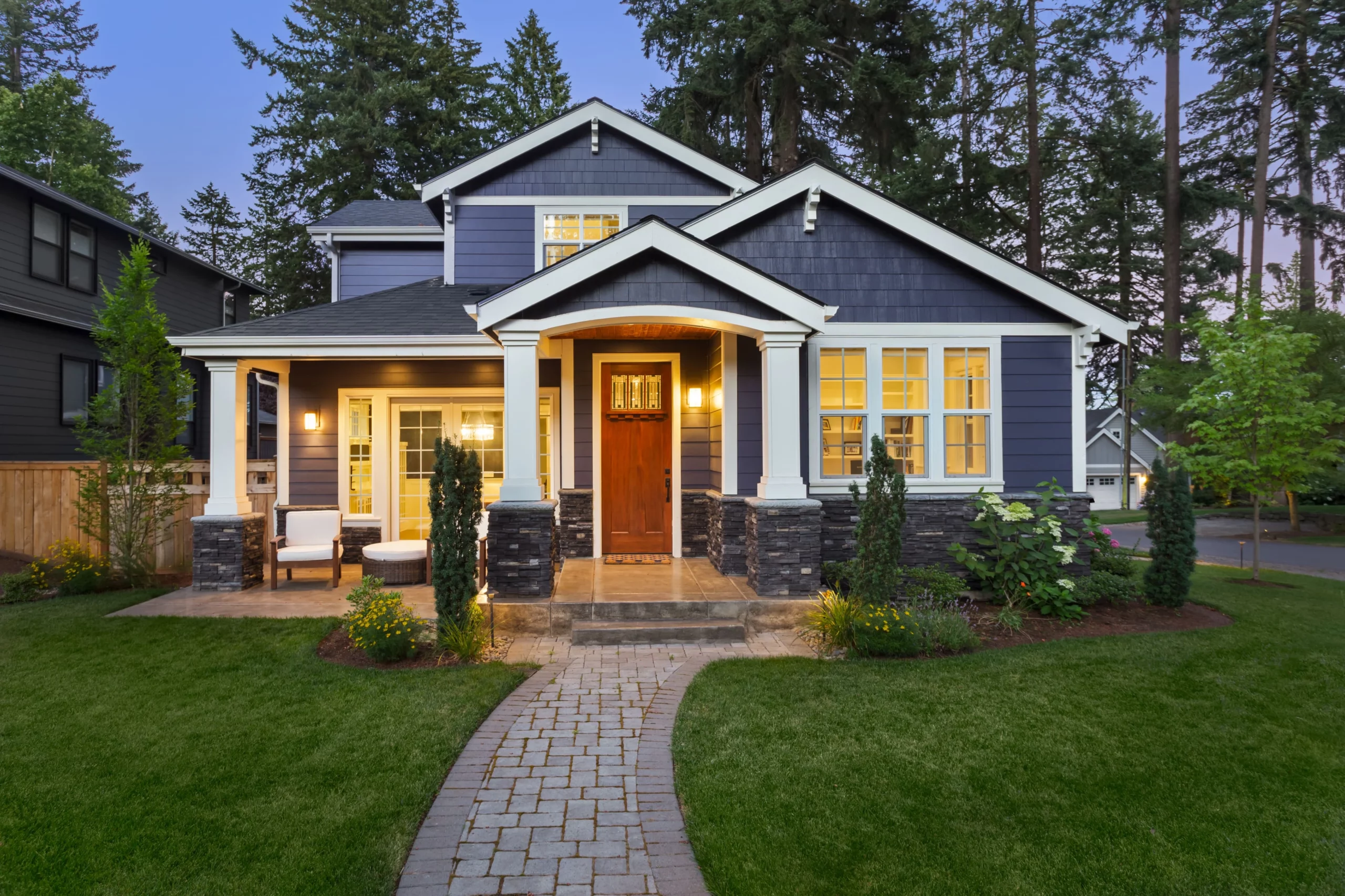Beautiful home exterior in evening with glowing interior lights and landscaping