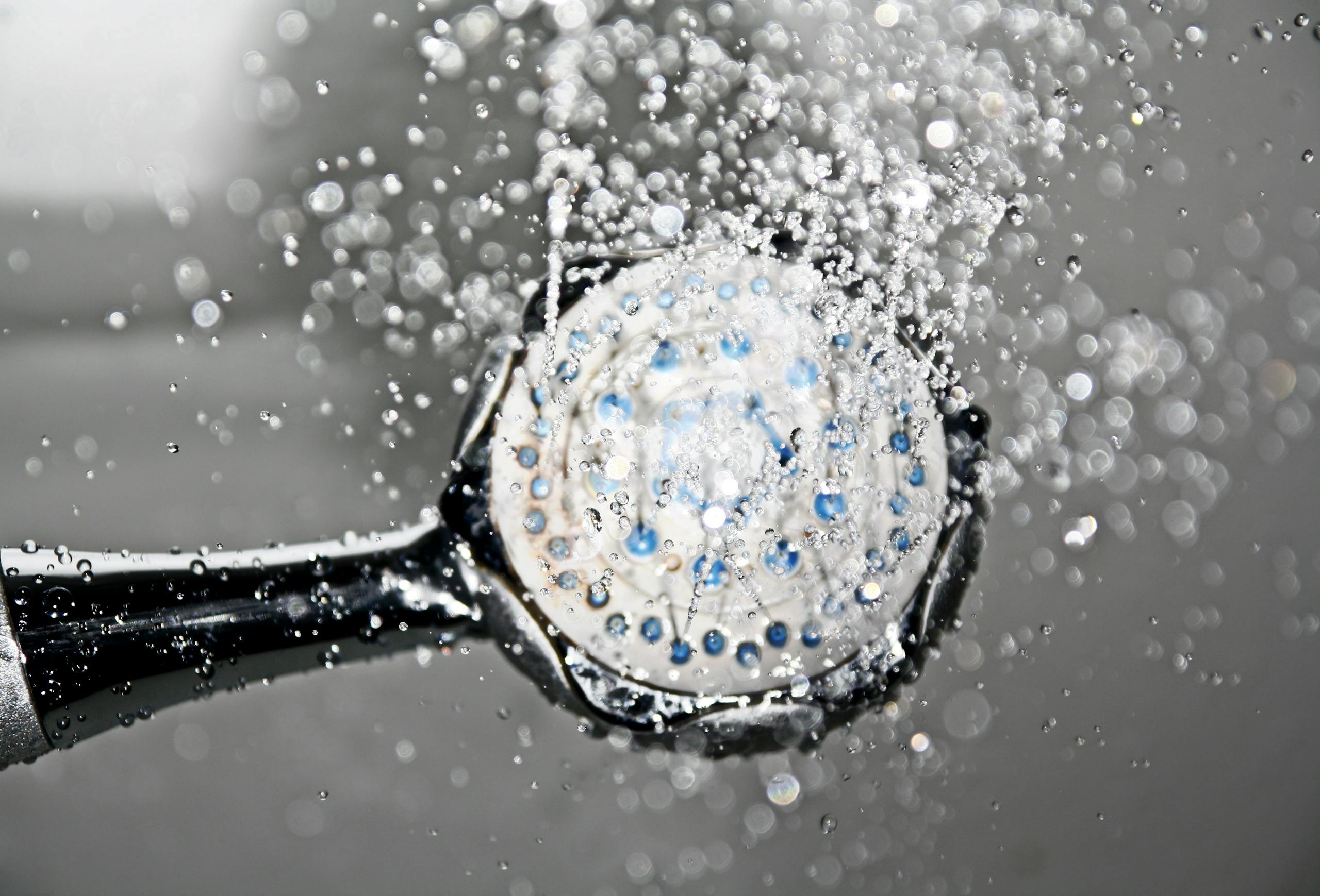 Close-up of a shower head releasing hot water droplets, creating a crisp and refreshing bathroom scene.